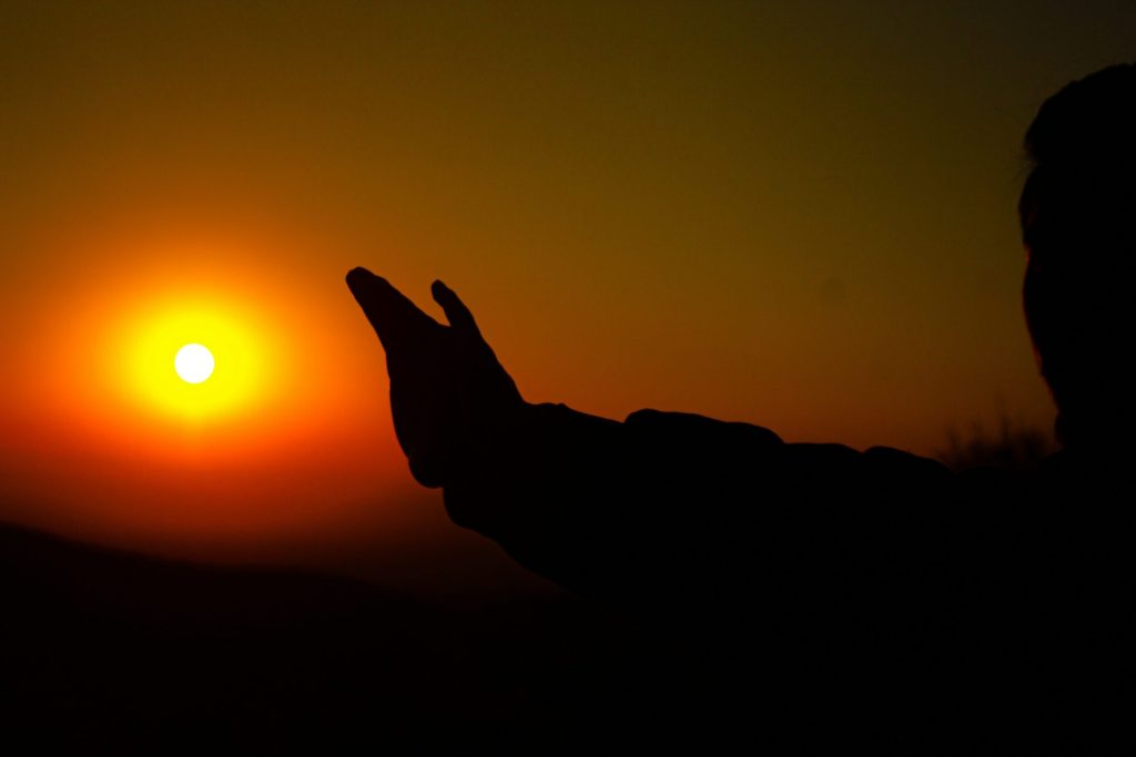 eine Person, die ihre Hand in die Sonne hält